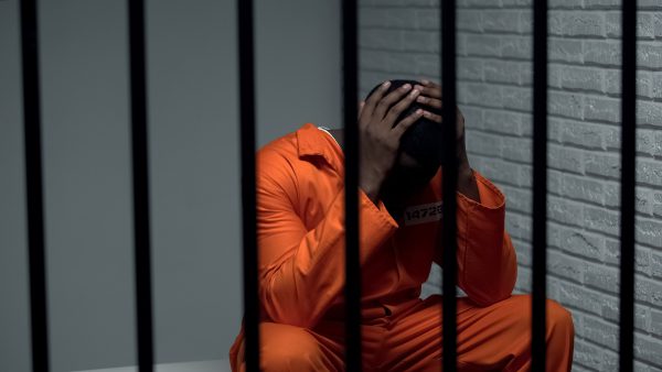 Black prisoner in distress and despair in prison cell